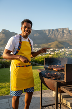 AMO Lekker Apron in Yellow with shweshwe print straps styled with Ocean Weave shorts — handcrafted in Cape Town