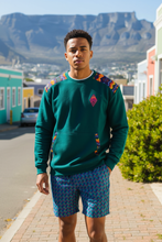 AMO Lekker Sweater in Green with shweshwe shoulder panels styled with Peacock Weave shorts — made in South Africa